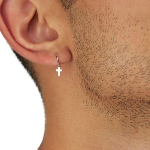 Close up of a cross ear ring for men wore by a male model on a white background