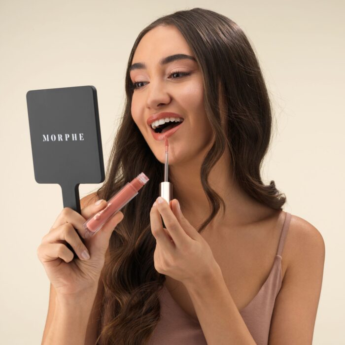 Cosmetics photo with a model smiling and applying lip gloss