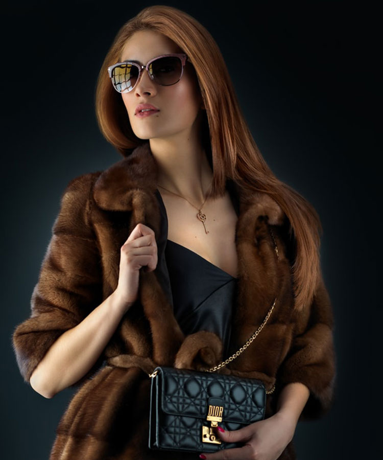 Model photography with brown fur and black bag on a black background