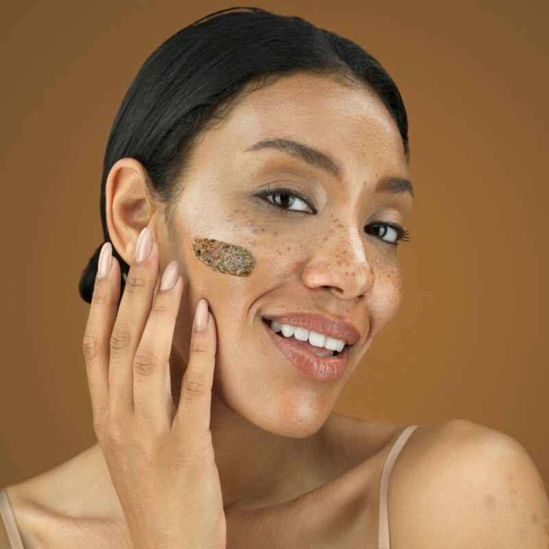 Model with a swatch on the face posing on a mocha background