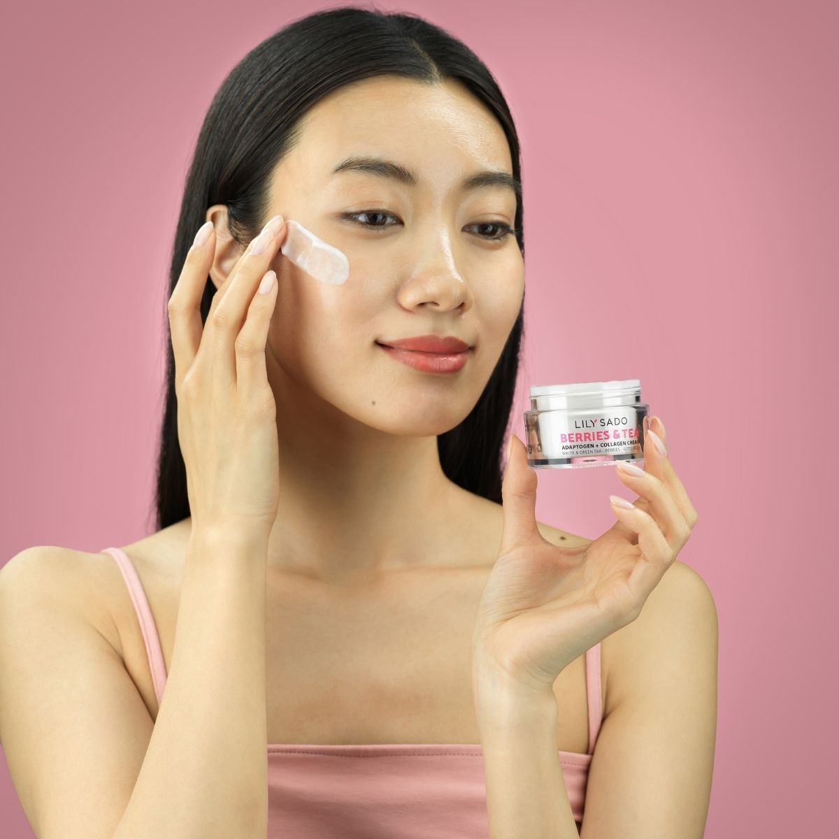 Asian model with cosmetics on a pink background showing the product