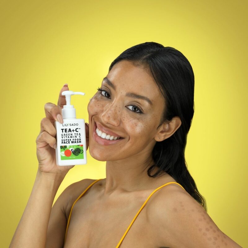 Afro-American Model is showing a smear of a beauty product on her face against a yellow background