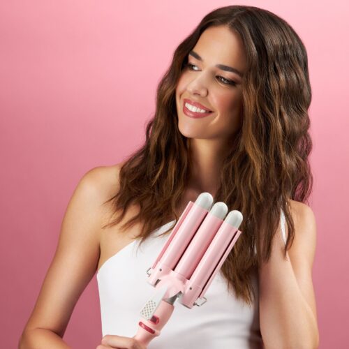 Product photography of a female model holding pink curling iron in her hand. Pink background. Commercial Photographer Isa Aydin. Nyc.