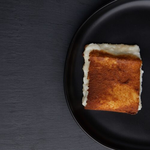 Food photography of bread with mayonnaise inside placed in a black serve ware shot on dark gray textured background.