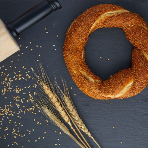 Food photography of a wheat bagel on a shelf with some wheatgrass on side