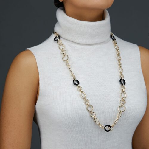 Female model wearing a necklace and turtle neck shirt on a gray background.