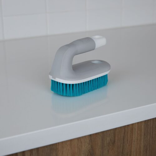 Blue scrub brush with gray and white handle placed on a table.