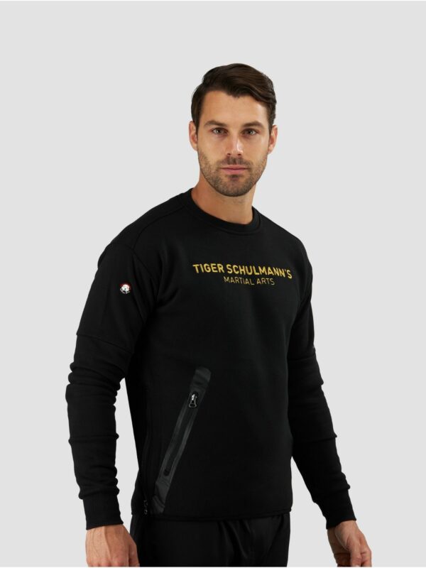 Clothing photography of a male model wearing sweat shirt in black with a “ Tiger Schulmann’s martial arts” text
