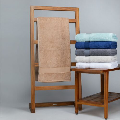 Creative lifestyle shot of five multi colored towels placed on a table and one towel hanged on a wooden frame.