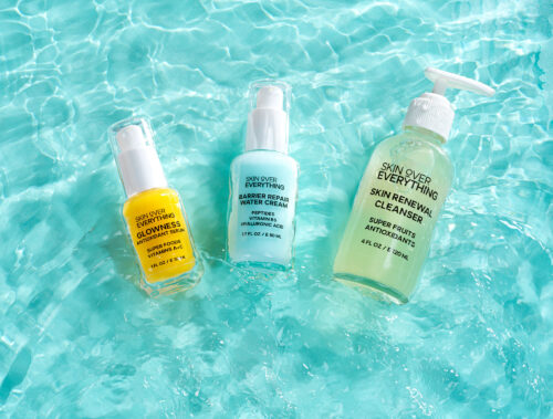 Three cosmetic products placed inside water creating a splash effect.