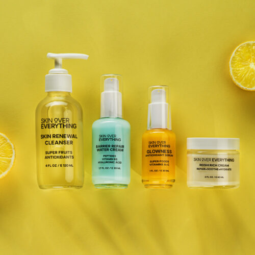 Four beauty products placed next to each other shot using gobo lighting and lemons on a yellow background.