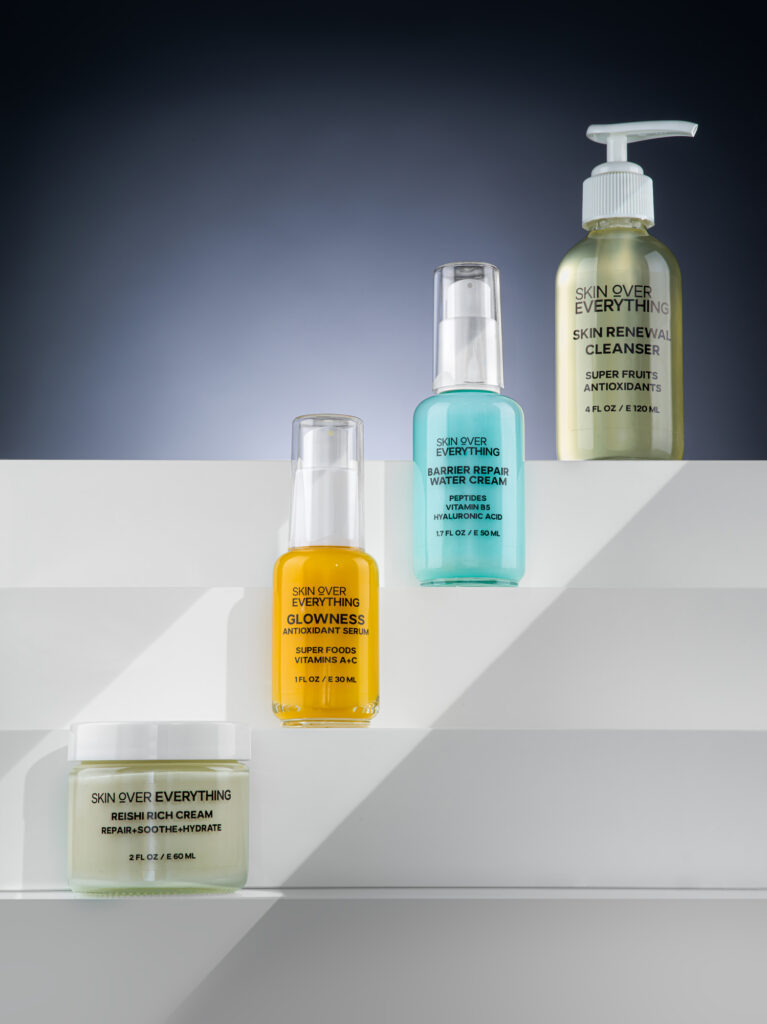 Four beauty products placed next to each other with each one placed at a different height shot using creative lighting.
