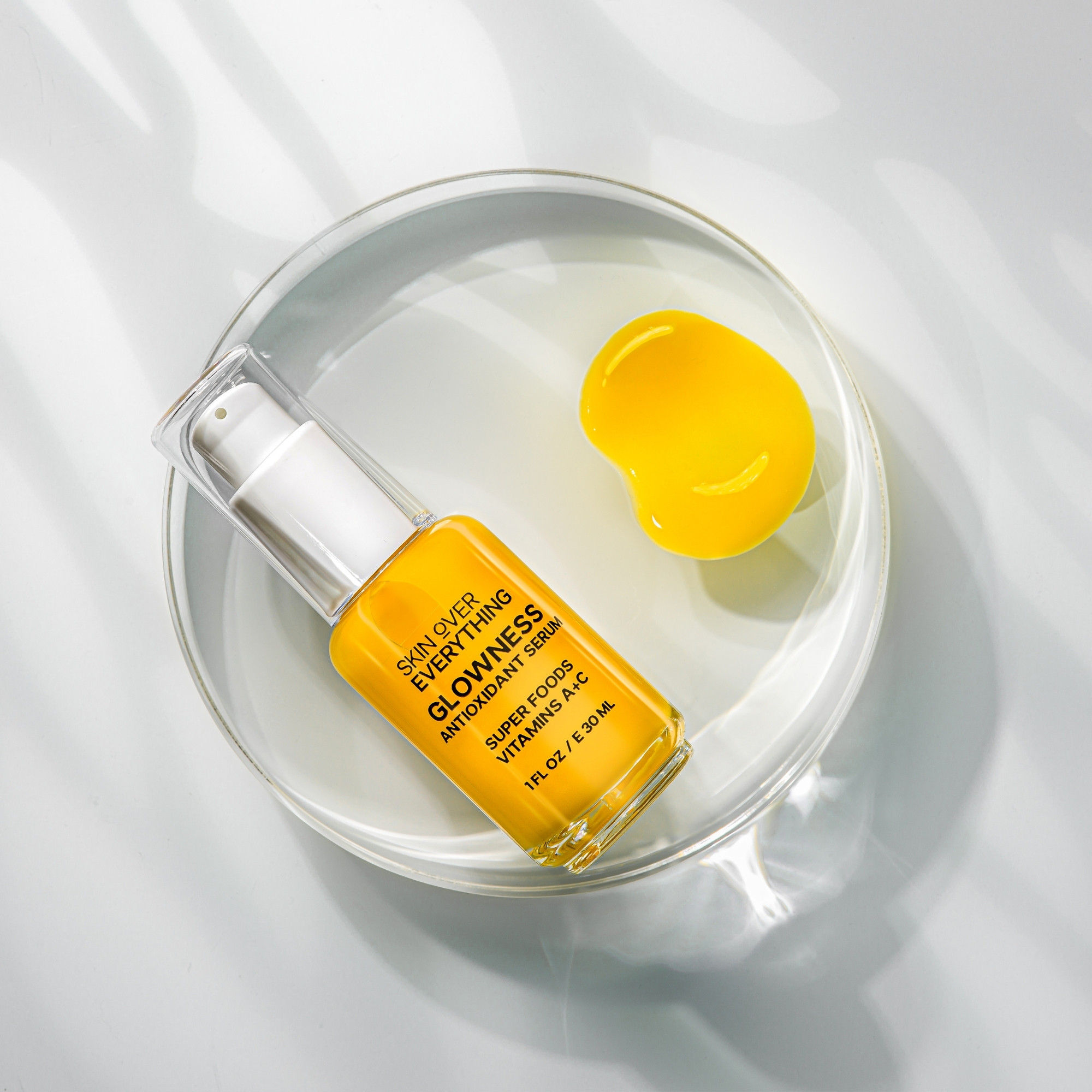 Antioxidant serum with yellow texture swatch placed on round acrylic block and shot using gobo lighting.