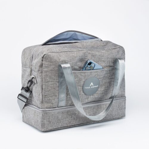 Action shot of a travel bag with open zip and an iPhone in Sierra blue color placed in the side pocket shot on a white background.