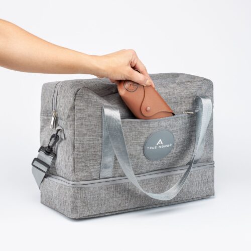 Action shot of a travel bag where a female hand model is placing glasses cover in the side pocket.