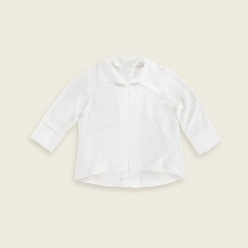 Lay flat clothing photography of a white shirt placed on a plain background
