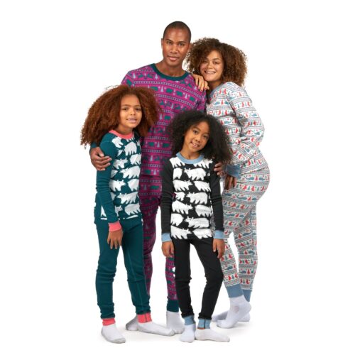 Husband, wife and two young girls wearing different colored pajamas and shirts posing for apparel photography on a white background.