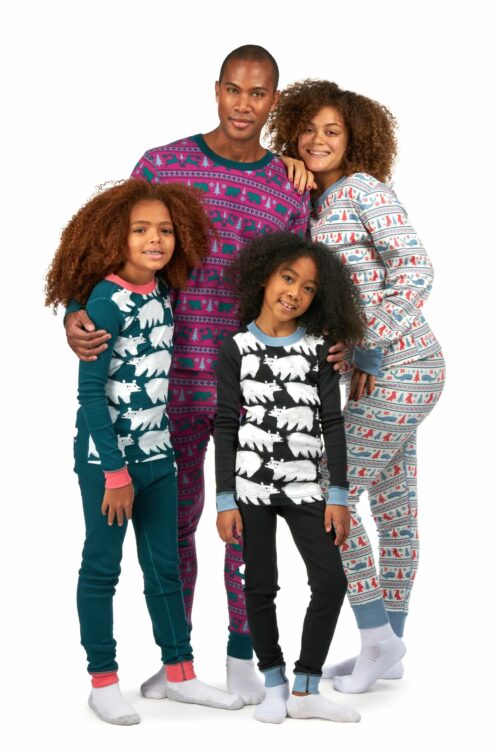 Black family of husband, wife and two young girls with curly hairs posing for clothing photography wearing different colored pajamas and shirts on a white background.