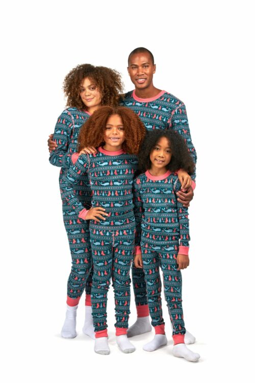 Black family of husband, wife and two young girls with curly hairs posing for clothing photography wearing pajamas and shirts on a white background.