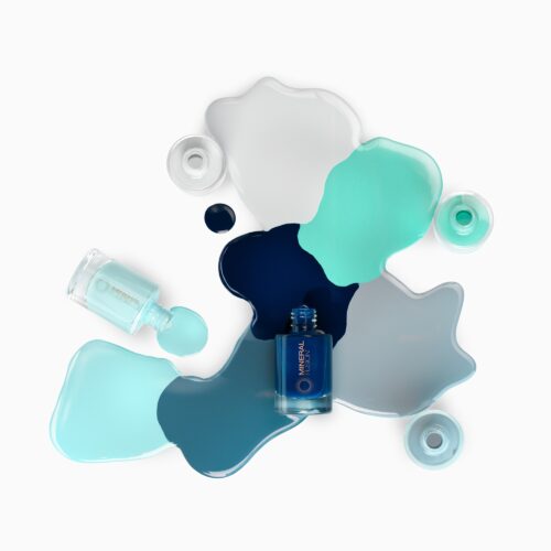 Creative nail polish photography in artsy pours settings of 4 nail polish bottles with different shades of blue and gray shot by beauty product photographer Isa Aydin.
