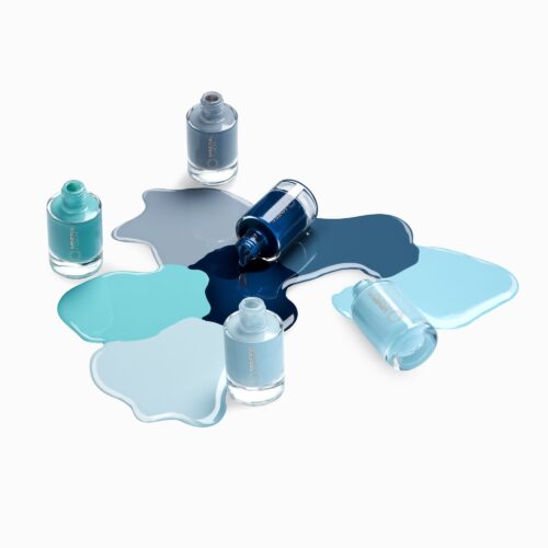Cosmetics photography of five nail polish bottles with different shades of blue in artsy pours setting by photographer Isa Aydin by Isa Aydin nj ny la