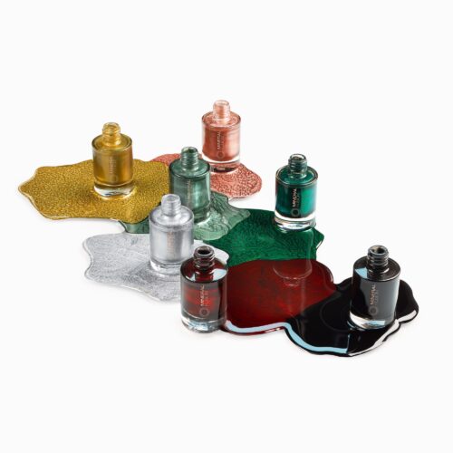 Cosmetics photography of seven nail polish bottles with artsy pours of each color setup using glitters by Isa Aydin nj ny la