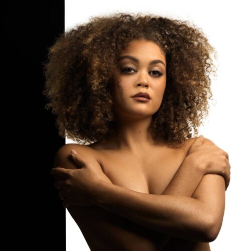 Naked black female model with curly hairs posing for a beauty shot for advertising photographer Isa Aydin.