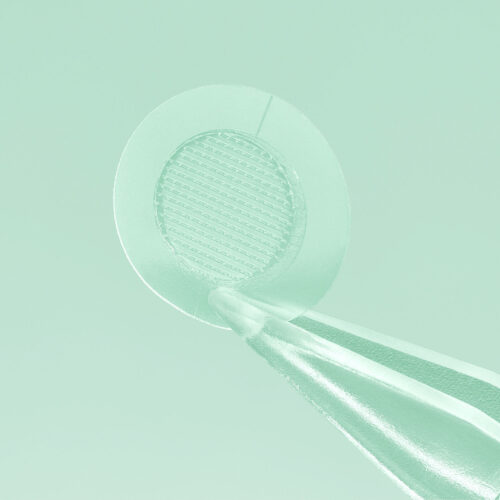 CloseUp photo of a face patch in a tweezer on green background for skincare product photography