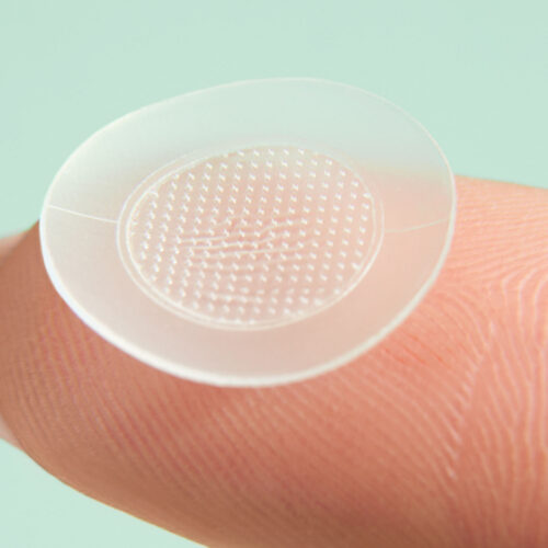 Face patch detail photo on a finger in a green background for skincare brand