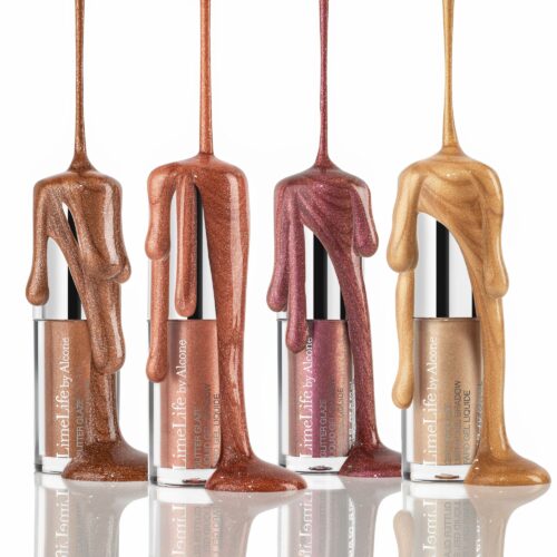 eyeshadow photography of Four tubes of liquid lip gloss in varying shades of brown and pink with metallic finishes, labeled 'LimeLife by Alcone.' The lip gloss is artistically dripping down the sides of the tubes, showcasing the glossy texture and colors. The tubes are reflected on a shiny surface below them.